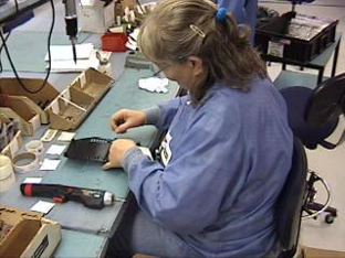 Woman sitting at a production station working on an assembly