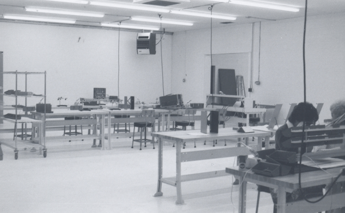 Black and white photo of a production floor with tables and assembly stations